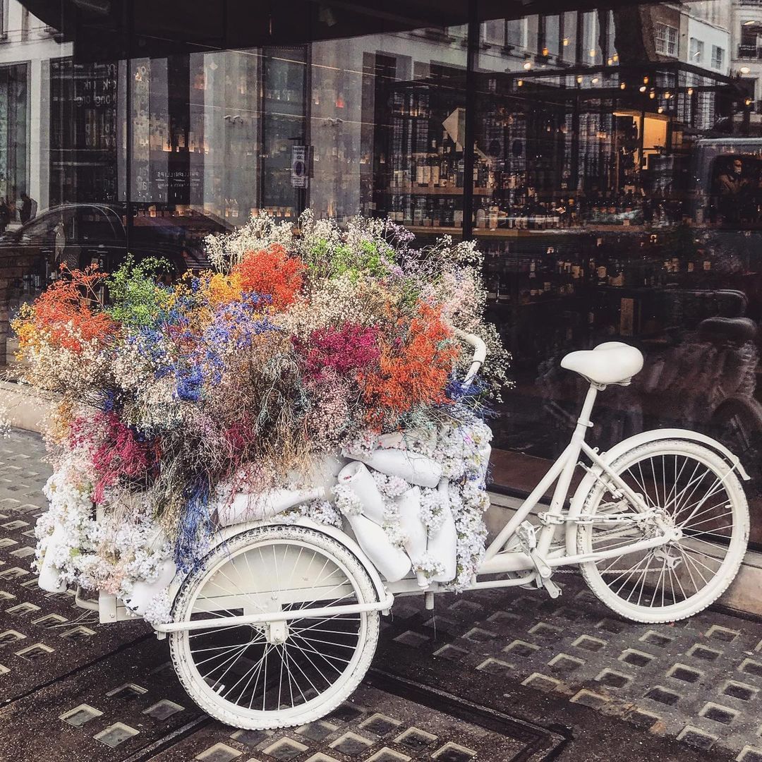 White delivery tricycle bike filled with flowers.